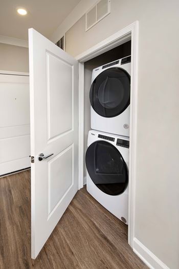 A white door is open to reveal a white washing machine.